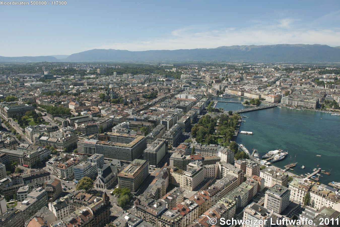 Genf / Genève, Blick aus dem Seebecken Rhone abwärts zur 'Ile Rousseau' (Norden: rechts).Stadtteil oben im Bild rechts: St-Gervais, vorne rechts: Eaux-Vives, Bildmitte und links: Cité-Centre. Erste grosse Brücke: Pont du Mont-Blanc, am Brückenkopf Bildmitte: Jardin Anglais.